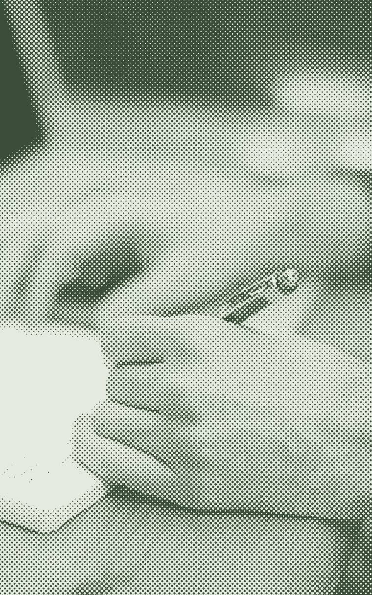 Hands writing in a notebook beside an open laptop