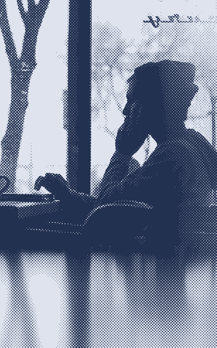 A silhouette resting head on hand beside a laptop at a window